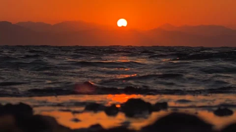 Dramatic Red Sunrise Reflecting on Rocky Sea Shoreline an calm waves on the Stock Footage 341909959