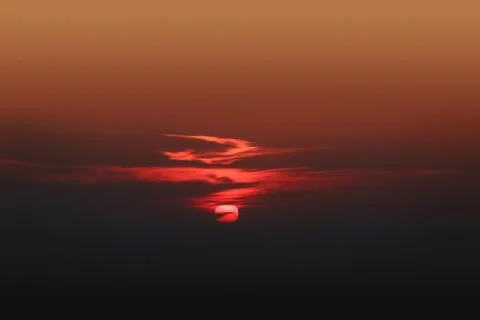 Dramatic red sunset with center sun and dark clouds Stock Photos