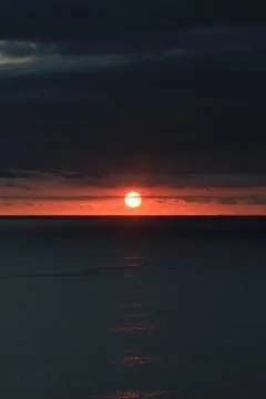 Dramatic red sunset over dark ocean horizon 스톡 사진