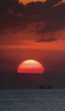 Dramatic Red Sunset Sun Above Ocean with Boat Silhouette Stock Photos