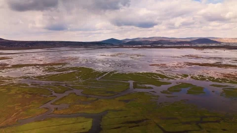 Dramatic reflection of white clouds on a calm wetland surface with distant mount Vidéo 332726801