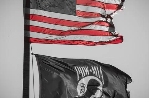 Dramatic Ripped USA Flag Flying above POA MIA Flag Stock Photos