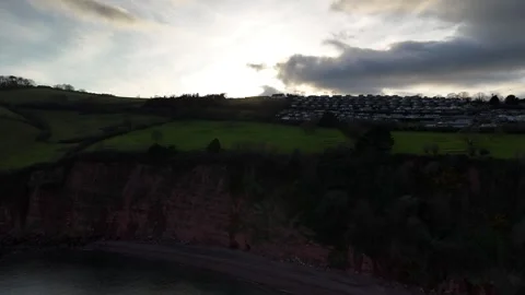 Dramatic rise over dark cliffs Shaldon South Devon to reveal sunset Stock Footage 305033195