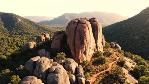 Dramatic rock formations dot a forested mountain landscape at sunset Video stock 333075796