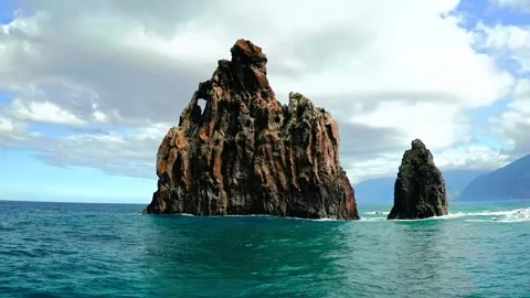 Dramatic rock formations rise from deep turquoise ocean waters under cloudy sky Stock Footage 343695932