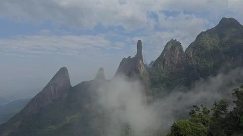 Dramatic Rock Formations Surrounded by Lush Jungle and Soft Clouds Stock Photos