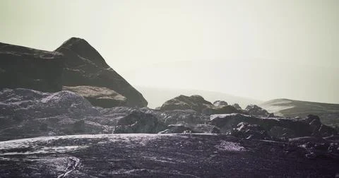 Dramatic rock formations under a hazy sky at a remote landscape Stock-Illustration