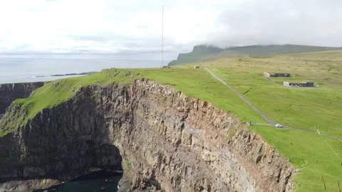Dramatic rocky cliffs and bright green fields at Akraberg Cape Stock Footage 340169217