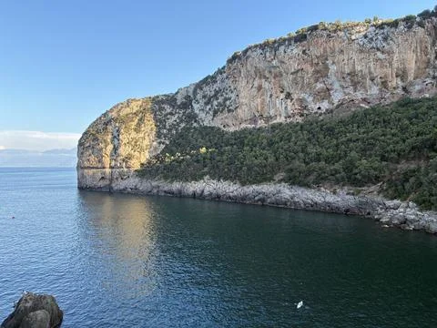 Dramatic rocky cliffs towering over the tranquil Mediterranean Sea in Bejaia Stock Photos