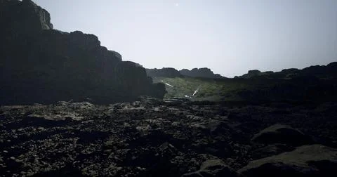Dramatic rocky landscape with distant waterfall under bright sunlight Stock-Illustration