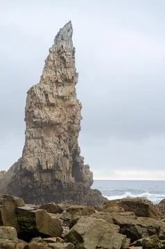 Dramatic rocky sea stack formation rising above ocean coastline in cloudy w.. Stock Photos