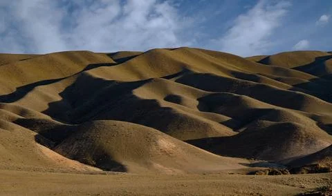 Dramatic rolling hills in golden tones with deep shadows at sunset. A minimal Stock Photos