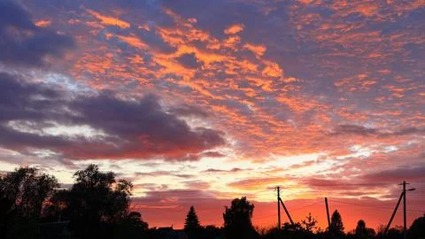 Dramatic rural landscape at dusk featuring glowing red clouds in the sky above Stock Photos