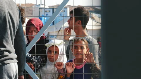 Dramatic Sad look of a refugee children behind the fence in a refugee camp. Vídeo Stock 158379999