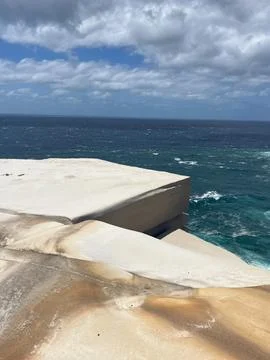 Dramatic sandstone cliffs meet the deep blue ocean under a cloudy sky Foto stock