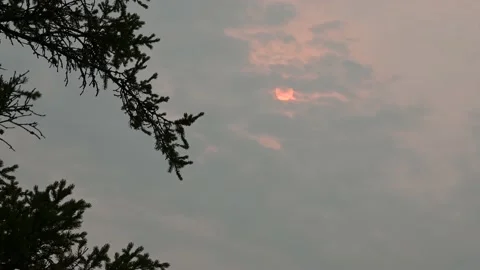 Dramatic scene with an orange sun colored by wildfire smoke and clouds Stock Footage 139591232