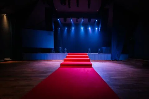Dramatic scene with a red carpet staircase leading up to a stage, illuminat.. Fotos Stock