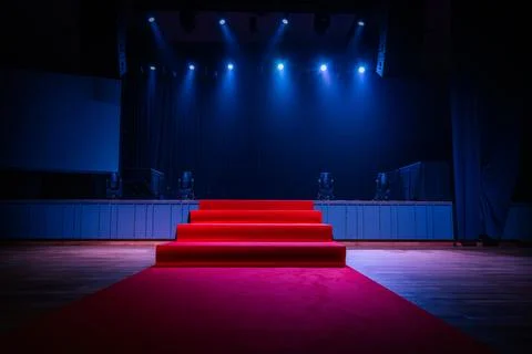 Dramatic scene with a red carpet staircase leading up to a stage, illuminat.. Stock Photos