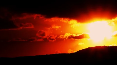 Dramatic, scenic sunset with strong orange color behind mountain and clouds Видео 86179467