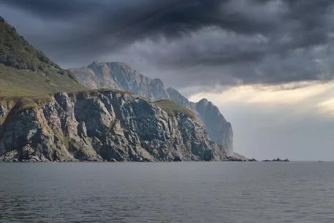 Dramatic sea cliffs and stormy sky on Kamchatka Peninsula coastline, Russia 库存照片