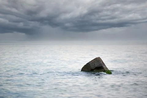 Dramatic seascape with cloudy storm warning, rain clouds on horizon, stone in Stock Photos