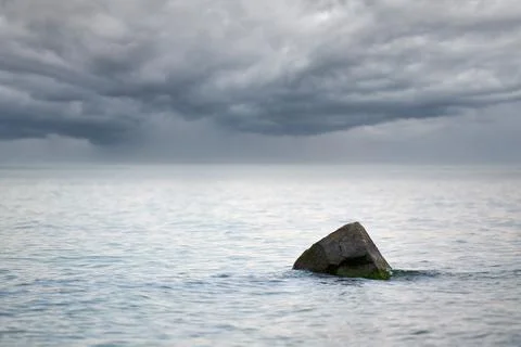 Dramatic seascape with cloudy storm warning, rain clouds on horizon, stone in Stock Photos