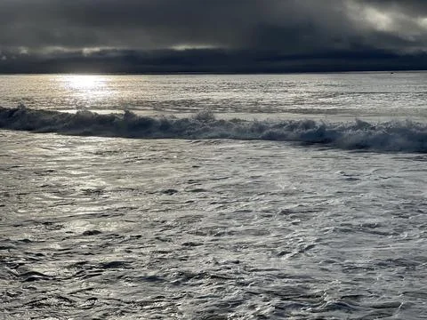 Dramatic Seascape at Dawn With Shimmering Waves and Cloudy Skies Stock Photos