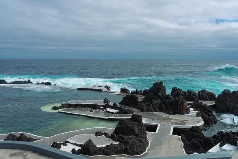 Dramatic seascape with natural pools and crashing ocean waves under a cloud.. Stock Photos