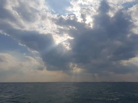 Dramatic seascape with sunlight streaming through clouds over calm ocean ho.. Stock Photos