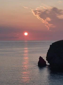 Dramatic Seascape Sunset with Cliff Silhouette - The vibrant red sun dips b.. Foto stock