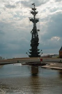 Dramatic Ship Monument And Tall Statue Over River With Modern Bridge 스톡 사진