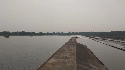 Dramatic shot from drone of boy with cycle waking on dam path. Stock Footage 254489278
