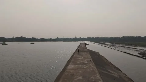 Dramatic shot from drone of boy with cycle waking on dam path. Stock Footage 254489374