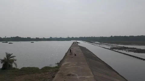 Dramatic shot from drone of boy with cycle waking on dam path. Stock Footage 254489670
