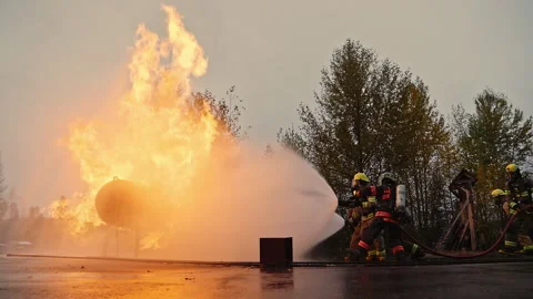 Dramatic shot of firefighters in formation marching forward and putting out fire Stock Footage 168460500