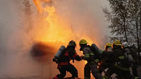 Dramatic shot of firefighters in formation putting out roaring fire in slow mo Stock Footage 168460530
