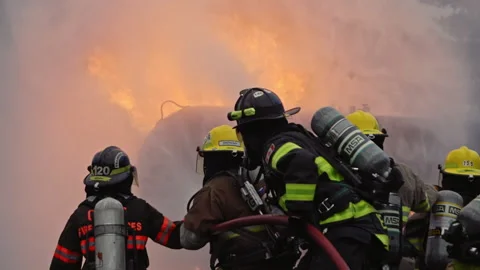 Dramatic shot of firefighters in formation putting out roaring fire in slow mo Stock Footage 168461010