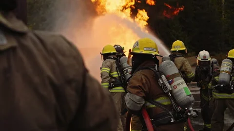Dramatic shot of firefighters in formation putting out roaring fire in slow mo Stock Footage 168461218