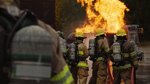 Dramatic shot of firefighters in formation putting out roaring fire in slow moti Stock Footage 168461318