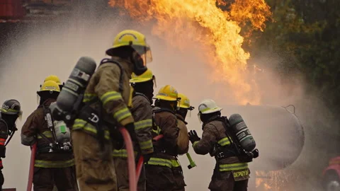 Dramatic shot of firefighters in formation putting out roaring fire in slow-mo Stock Footage 168461765