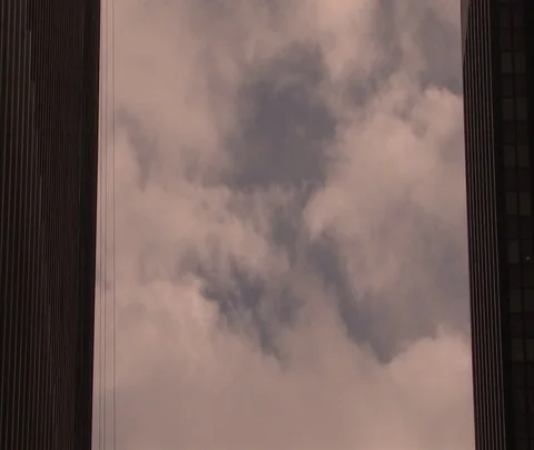 Dramatic shot of fluffy clouds seen between two dark Manhattan skyscrapers. Stock Footage 86749361