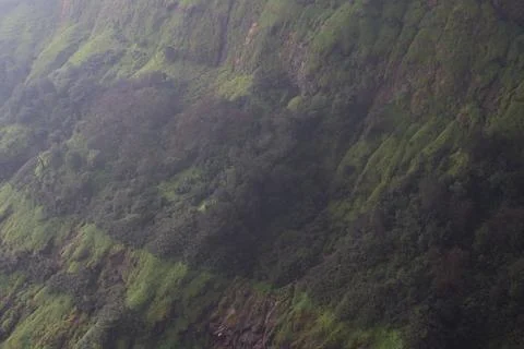 A dramatic shot of the lush green cliffs of Matheran enveloped in light mist Stock Photos