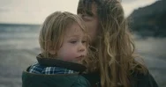 Dramatic Shot Of Mother With Toddler On Windy Beach In Winter Stock Footage