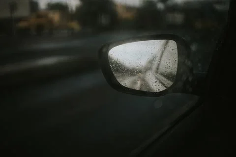 Dramatic shot of the side mirror of a car reflecting the road during the rain Stock Photos