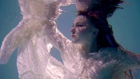 Dramatic shot of sinking romantic girl inside water of lake, face with ripple of 스톡 동영상 89580920