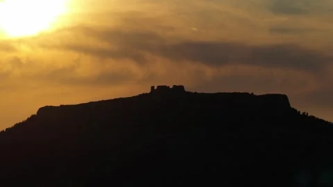 A dramatic silhouette of ancient ruins atop a hill is seen against a vivid Stock Footage 346700193