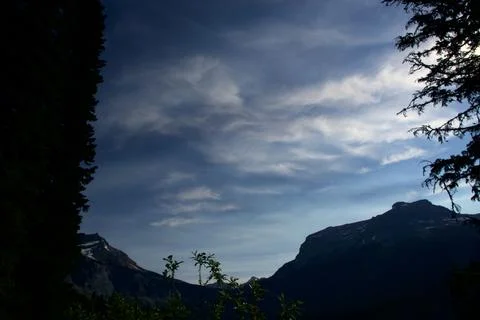 Dramatic Silhouette of Mountain Ranges Under a Cloudy Alpine Sky Stock Photos