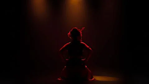 Dramatic Silhouette of Traditional Dancer Under Red Stage Lighting Stock Photos