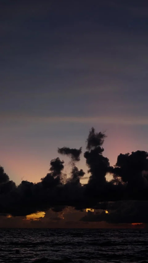Dramatic silhouettes of dark storm clouds gather over a tranquil ocean horizon Stock Footage 310487817