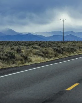 Dramatic sky above empty highway and mountains Stock Photos